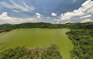 Panorama tabiat gölü ya da gölet manzaralı yeşil tropikal yağmur ormanlarının insansız hava aracı görüntüsü ve mavi gökyüzü.