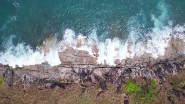 Hava dalgaları kayalık kayalıklara çarpıyor. Su sıçraması ve beyaz köpükle. Phuket Adası Tayland Yüksek Açılı Manzarası 'nda güzel dalgalar