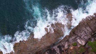 Hava dalgaları kayalık kayalıklara çarpıyor. Su sıçraması ve beyaz köpükle. Phuket Adası Tayland Yüksek Açılı Manzarası 'nda güzel dalgalar