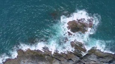 Hava dalgaları kayalık kayalıklara çarpıyor. Su sıçraması ve beyaz köpükle. Phuket Adası Tayland Yüksek Açılı Manzarası 'nda güzel dalgalar