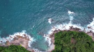Tayland 'ın Phuket Adası' nda kayalık taşlara çarpan hava manzaralı yavaş çekim dalgaları.