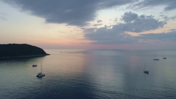 セーリングボートと海の表面の上のカラフルな夕日プーケットの海を飛ぶ空中ビュードローン水面に太陽の黄金の光海の上の夕日シースケープ夏と旅行休暇のコンセプト — ストック動画