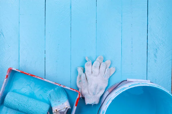 Paint brush in color tray and paint bucket,glove on blue wooden background