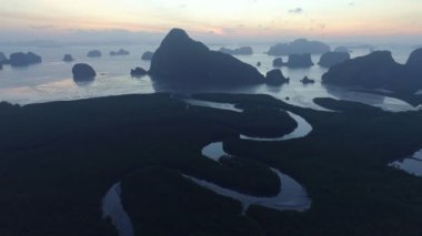 Sabahın ilk ışıklarıyla deniz ve mangrov ormanlarının üzerinden doğan güzel gökyüzünün insansız hava görüntüsü.