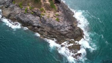 Aerial view Top down seashore big wave crashing on rock cliff, Beautiful dark sea surface in sunny day summer background, Amazing seascape top view seacoast,High quality footage