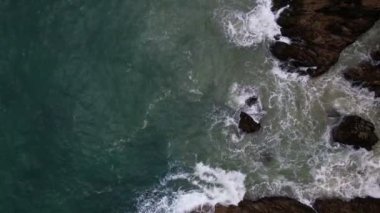 Aerial view Top down seashore big wave crashing on rock cliff, Beautiful dark sea surface in sunny day summer background, Amazing seascape top view seacoast,High quality footage