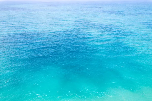 Aerial view of a blue sea water background and sun reflections. Aerial flying drone view and shadow clouds on sea surface,water texture on ocean, Aerial photography. Birds eye view. Sea