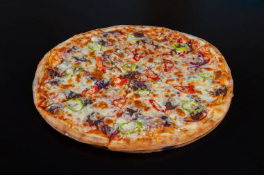Siyah arka planda et ve sebzeli yakın plan pizza.
