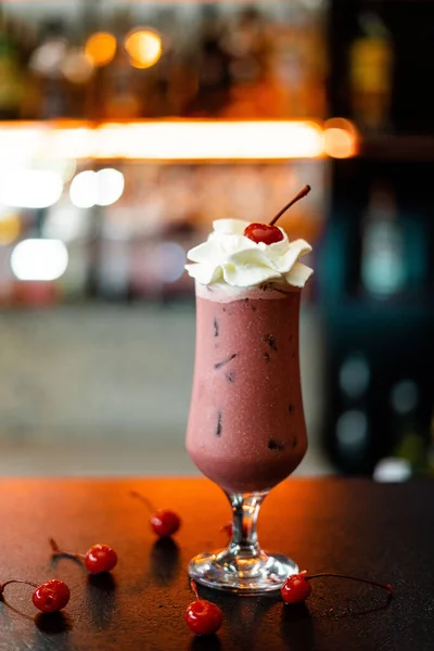 Glass of berry smoothie on bar counter with cherries around. Selective focus