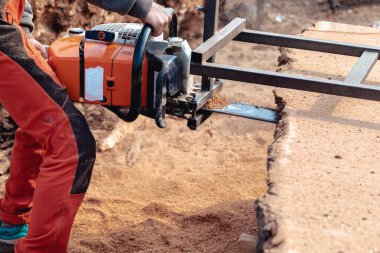 Tahta yapmak için ağaç gövdesini elektrikli testereyle kesen oduncunun yakın çekimi.