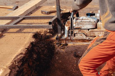 Tahta yapmak için ağaç gövdesini elektrikli testereyle kesen oduncunun yakın çekimi.