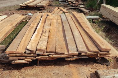 Yığınla kereste. Katlanmış ahşap. Kapalı tahta. Depoda üst üste istiflenmiş tahta kalaslar. İnşaatta kullanmak için kereste.