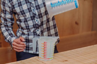 Marangoz, sıvı kaba epoksi reçinesi döküyor. El yapımı reçine ve ahşap masa..