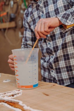 Marangoz epoksi reçinesi hazırlıyor. El yapımı reçine ve ahşap masa.