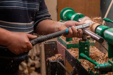 Marangoz torna tezgahında ahşap yapıyor. Torna tezgahına keski şamdanı oyan kişi