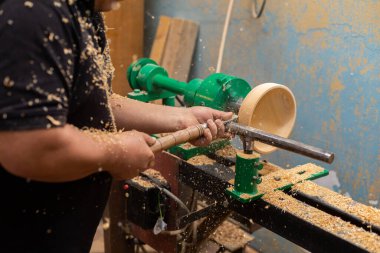 Marangoz torna tezgahında ahşap yapıyor. Torna tezgahına keski şamdanı oyan kişi