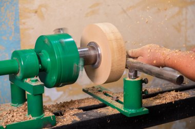 Marangozun torna tezgahına odun çevirdiği yakın plan. Torna tezgahına keski şamdanı oyan kişi