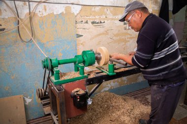 Marangoz torna tezgahında ahşap yapıyor. Torna tezgahına keski şamdanı oyan kişi