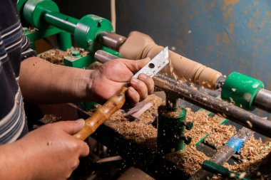 Marangozun torna tezgahına odun çevirdiği yakın plan. Torna tezgahına keski şamdanı oyan kişi