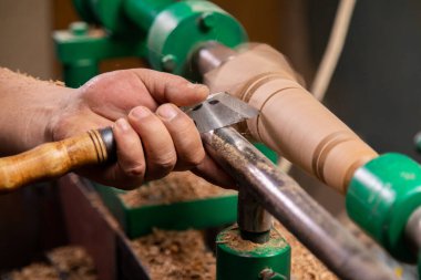 Marangozun torna tezgahına odun çevirdiği yakın plan. Torna tezgahına keski şamdanı oyan kişi