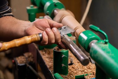 Marangozun torna tezgahına odun çevirdiği yakın plan. Torna tezgahına keski şamdanı oyan kişi