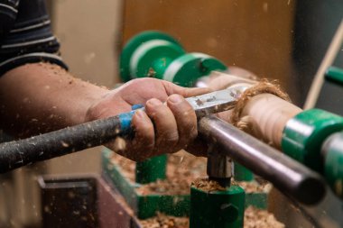 Marangozun torna tezgahına odun çevirdiği yakın plan. Torna tezgahına keski şamdanı oyan kişi