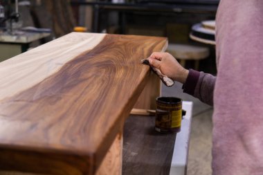 Marangoz, ahşap bir masayı koruyucu keten tohumu yağıyla kaplıyor. Ahşap masa yapma süreci
