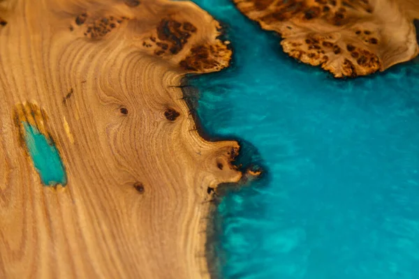 Texture of handmade wooden river table with decorative epoxy blue resin