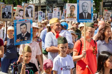 Bishkek, Kırgızistan - 9 Mayıs 2022: 9 Mayıs Zafer Günü ölümsüz alay. İnsanlar büyük vatanseverlik savaşına katılan akrabalarının afiş resimleriyle köşe yazıları yazıyorlar.