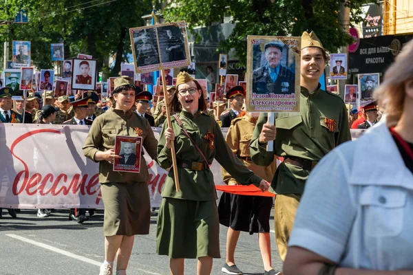 Bishkek, Kırgızistan - 9 Mayıs 2022: 9 Mayıs Zafer Günü ölümsüz alay. İnsanlar büyük vatanseverlik savaşına katılan akrabalarının afiş resimleriyle köşe yazıları yazıyorlar.