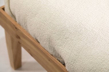 Beyaz arka planda izole edilmiş ahşap bir komodinin üzerinde el yapımı sütlü keçeli yastık.