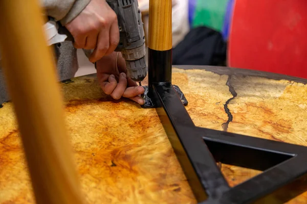 Closeup of carpenter screwing the table leg with a screwdriver