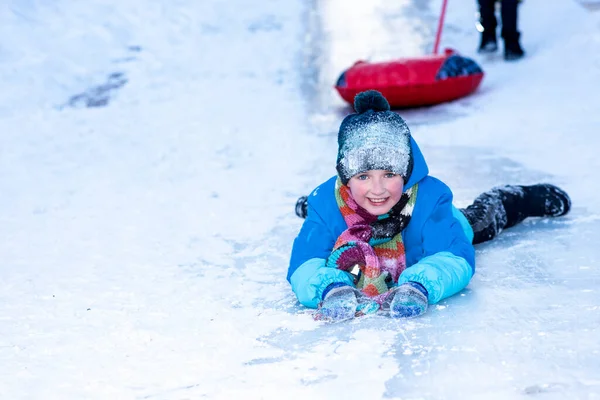 冬天的时候 男孩穿着蓝色夹克 肚子上滑着冰 高兴极了 — 图库照片