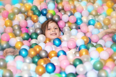 Çocuk havuzda, oyun merkezinde plastik toplarla yatıyor.