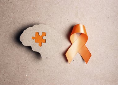 Dünya Çoklu Skleroz Günü. Kahverengi arka planda turuncu farkındalık şeridi ve beyin sembolü.