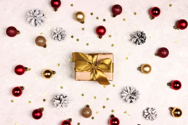 Altın kurdeleli bir hediye, açık mermer arka planda toplar ve koniler. Üst görünüm bileşimi.