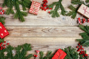 Noel çerçevesi köknar dalları, böğürtlenler ve ahşap arka planda hediyelerden yapılmıştır. Boşluğu kopyala, üst görünüm.