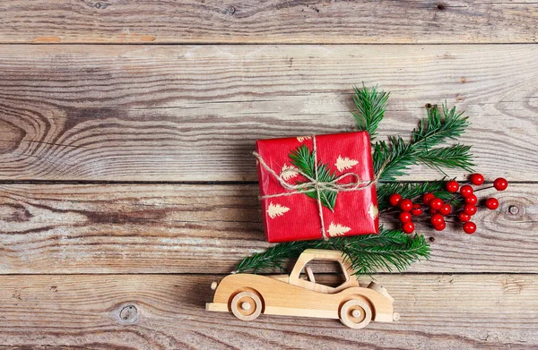 木制玩具车 屋顶上有礼物盒和冷杉树枝 木制背景 带复制空间的自上而下圣诞作文 — 图库照片