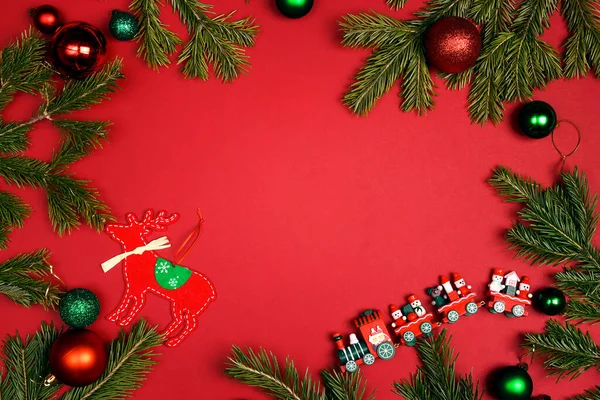 圣诞框架由冷杉树枝和红色背景的玩具装饰制成 复制空间 顶视图 平面层 免版税图库图片