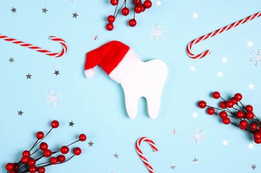 Noel Baba şapkalı beyaz dişler mavi arka planda Noel süsleriyle çevrili. Dişçi Mutlu Noeller ve yeni yıl konsepti. Üst manzara, düz uzanma.
