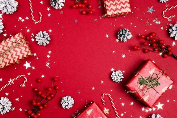 赤い背景に贈り物や装飾で作られたクリスマスのフレーム コピースペース トップビュー — ストック写真