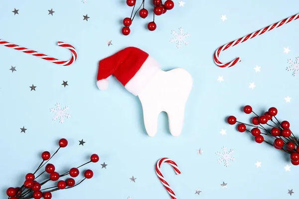 Noel Baba şapkalı beyaz dişler mavi arka planda Noel süsleriyle çevrili. Dişçi Mutlu Noeller ve yeni yıl konsepti. Üst manzara, düz uzanma.