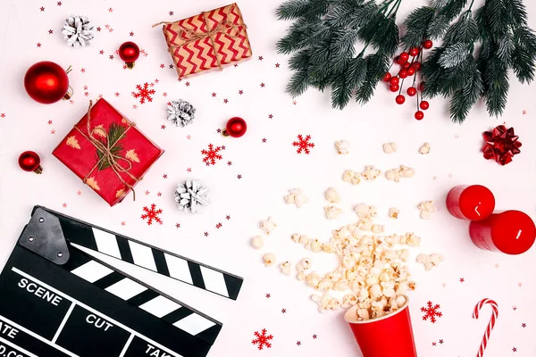 Beyaz arka planda Noel süsleri, hediyeler ve patlamış mısırlı film alkışları. Kış tatili boyunca sinemanın keyfini çıkarın..