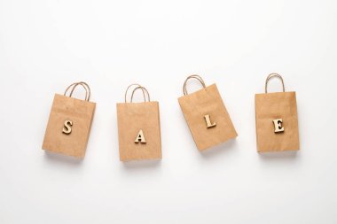 Kağıt alışveriş torbaları ve beyaz arka planda kelime satışı. Satın alma ve satış konsepti.