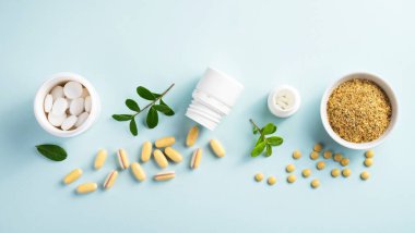 Kavanozlarda vitaminler ve bitkisel takviyeler. Mavi arka planda yeşil bir bitki var.