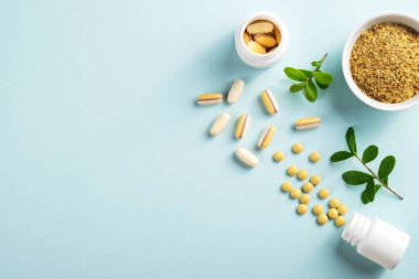 Kavanozlarda vitaminler ve bitkisel takviyeler. Mavi arka planda yeşil bir bitki var.