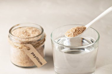 Kavanozda muz kabuğu, yazıtlarda Psyllium ve arka planda bir bardak su var..