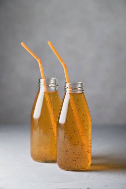 Çarkıfelek meyveli içecek, biber tohumlu cam şişelerde tüpler. Gri arkaplan