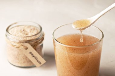 Kavanozda muz kabuğu, yazıtlarda Psyllium ve arka planda bir bardak su var..