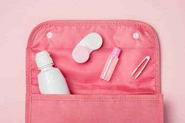 Kontakt lensler için aksesuarlar: Çözüm, kap, cımbız, kozmetik çanta. Pembe arkaplan, kopyalama alanı